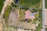Discover this expansive property featuring a large, multi-winged home with a terracotta tile roof, surrounded by lush greenery and mature trees.