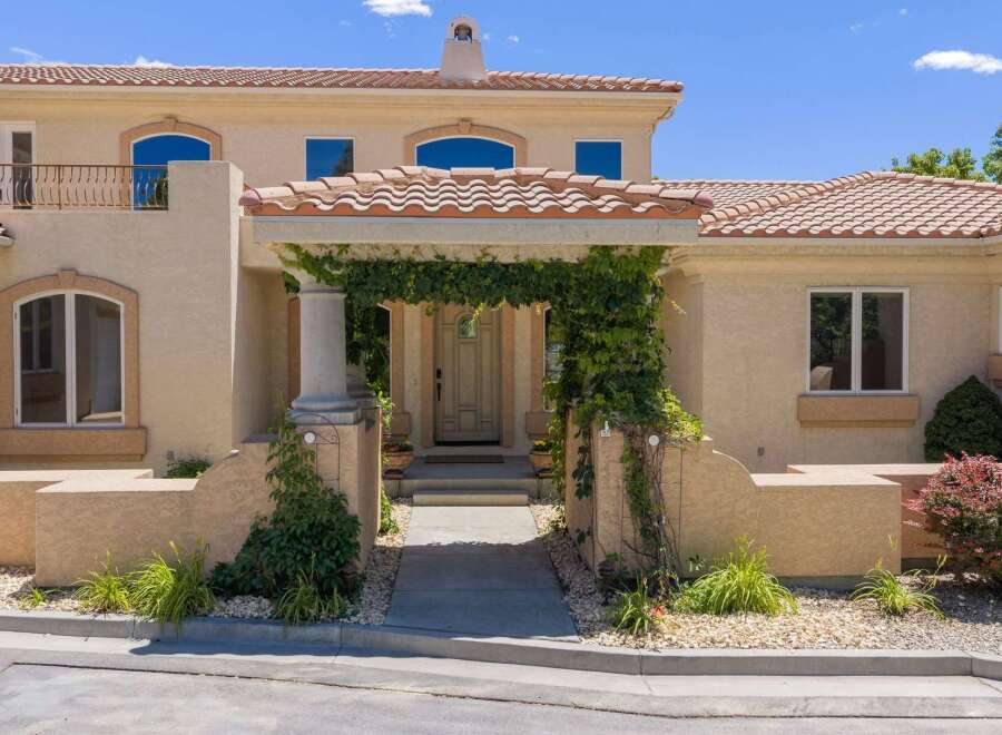 Welcome to this stunning home featuring a charming vine-covered entryway leading to a grand front door.