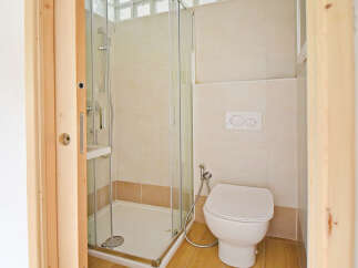 This modern bathroom features a sleek glass-enclosed shower and a clean white toilet with a bidet spray.