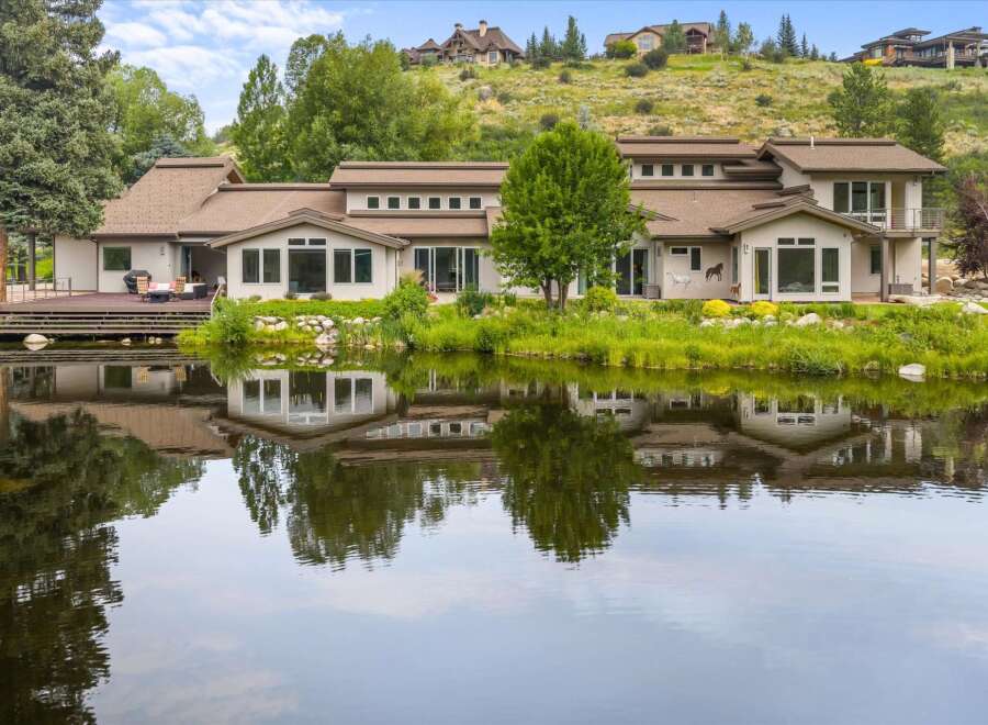 Experience luxury living with this stunning estate featuring a sprawling deck overlooking a serene lake.