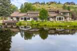 Experience luxury living with this stunning estate featuring a sprawling deck overlooking a serene lake.