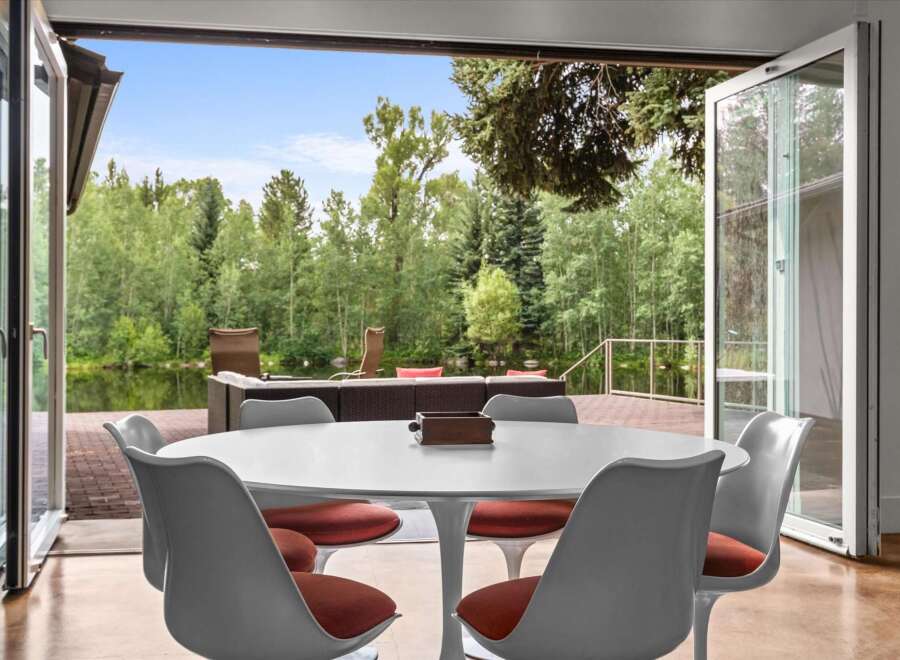 Enjoy seamless indoor-outdoor living with this stunning dining area featuring a modern tulip table and chairs.