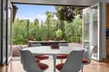 Enjoy seamless indoor-outdoor living with this stunning dining area featuring a modern tulip table and chairs.