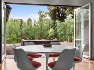 Enjoy seamless indoor-outdoor living with this stunning dining area featuring a modern tulip table and chairs.