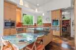 Experience a unique culinary space with this stunning kitchen, featuring a captivating glass island countertop with a mesmerizing water and fish motif.