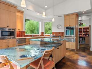 Experience a unique culinary space with this stunning kitchen, featuring a captivating glass island countertop with a mesmerizing water and fish motif.