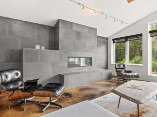 Experience modern luxury in this stunning living room, featuring a sleek, floor-to-ceiling concrete fireplace as the centerpiece.