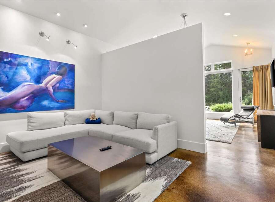 Experience modern living in this spacious living area, featuring a large sectional sofa and a striking abstract artwork.