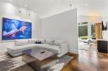 Experience modern living in this spacious living area, featuring a large sectional sofa and a striking abstract artwork.