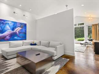 Experience modern living in this spacious living area, featuring a large sectional sofa and a striking abstract artwork.
