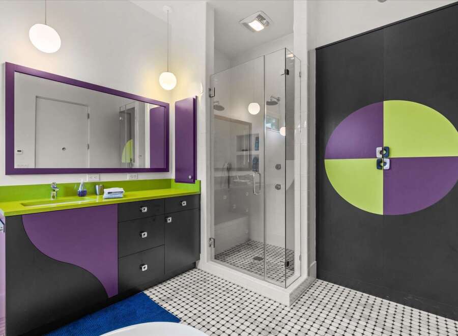 This modern bathroom features a vibrant and playful design, highlighted by a striking purple and lime green vanity with a sleek countertop.