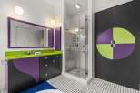 This modern bathroom features a vibrant and playful design, highlighted by a striking purple and lime green vanity with a sleek countertop.