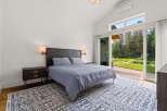 Experience luxurious living in this stunning bedroom featuring a king-sized bed with a dark wood headboard and plush grey bedding.