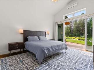 Experience luxurious living in this stunning bedroom featuring a king-sized bed with a dark wood headboard and plush grey bedding.