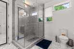 Experience modern luxury in this stunning bathroom featuring a spacious glass-enclosed shower with dual showerheads and elegant grey tilework.