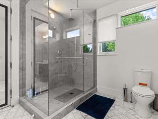 Experience modern luxury in this stunning bathroom featuring a spacious glass-enclosed shower with dual showerheads and elegant grey tilework.