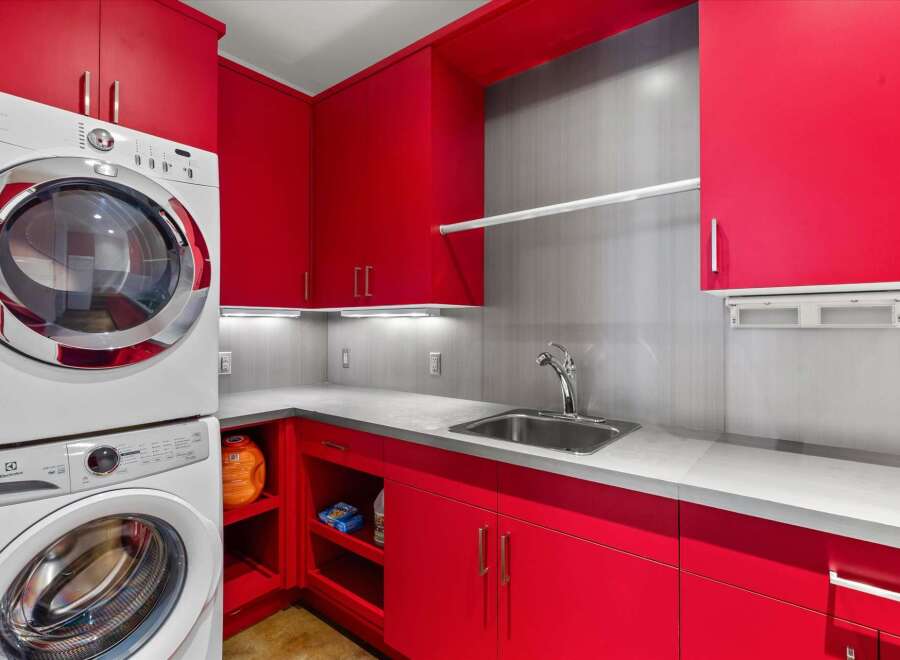 This laundry room boasts vibrant red cabinetry, offering a bold and stylish aesthetic.