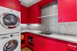 This laundry room boasts vibrant red cabinetry, offering a bold and stylish aesthetic.