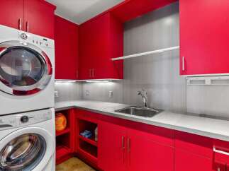 This laundry room boasts vibrant red cabinetry, offering a bold and stylish aesthetic.