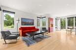 Experience modern living in this bright and airy living room, featuring a vibrant orange sofa and sleek black armchairs.