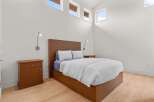 This modern bedroom features a sleek wooden platform bed with integrated storage, complemented by matching nightstands and a minimalist headboard.