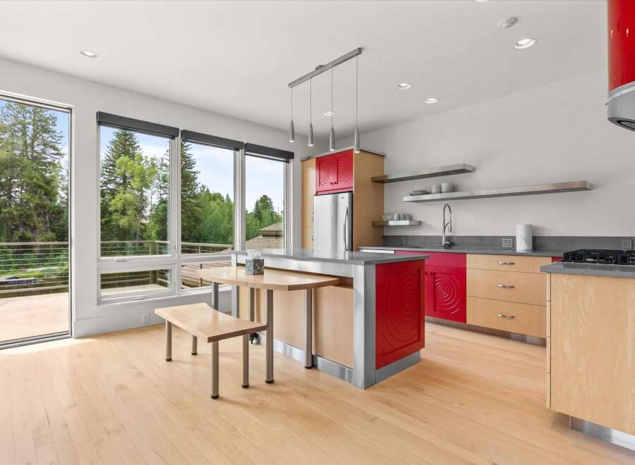 Experience modern living in this stunning kitchen featuring vibrant red cabinetry and sleek stainless steel accents.
