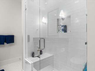 Experience luxury in this modern bathroom featuring a spacious walk-in shower with sleek white subway tile and a built-in bench.