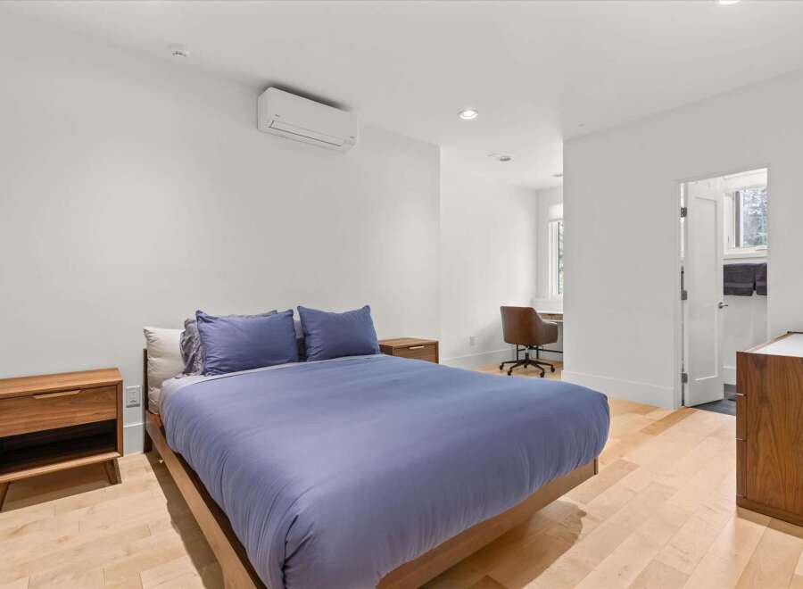 Experience modern comfort in this serene bedroom, featuring a plush blue duvet and matching pillows on a sleek wooden bed frame.