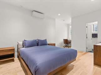 Experience modern comfort in this serene bedroom, featuring a plush blue duvet and matching pillows on a sleek wooden bed frame.