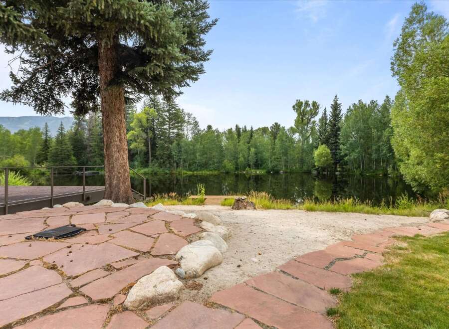 Enjoy serene lakefront living with this stunning property, featuring a spacious stone patio perfect for outdoor entertaining.