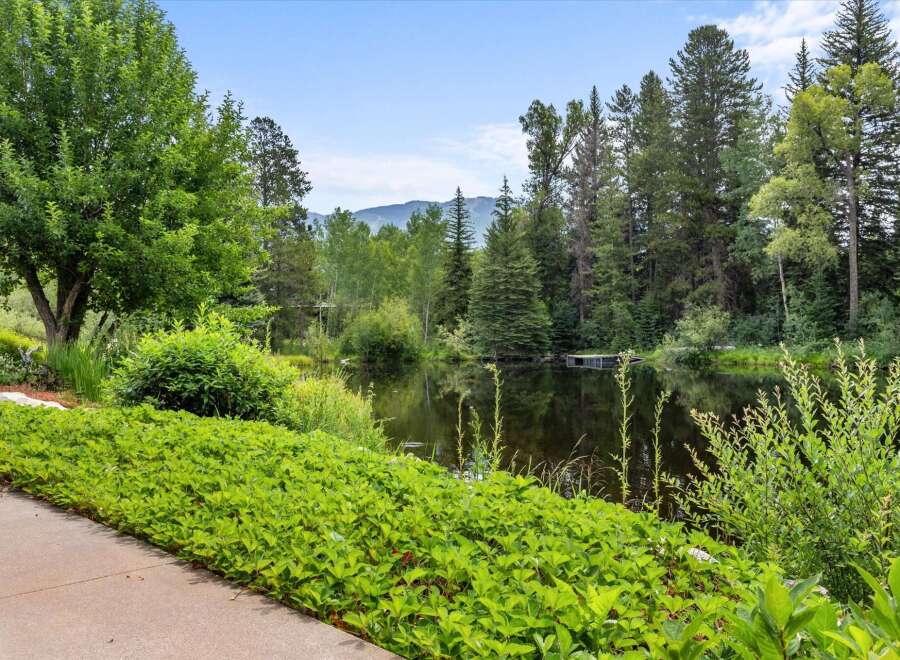Discover serene living with this picturesque property featuring a tranquil pond surrounded by lush greenery and mature trees.