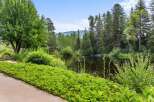 Discover serene living with this picturesque property featuring a tranquil pond surrounded by lush greenery and mature trees.
