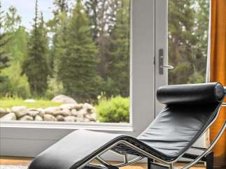 Experience ultimate relaxation in this modern living space, featuring a sleek black leather chaise lounge positioned perfectly to enjoy the breathtaking views.