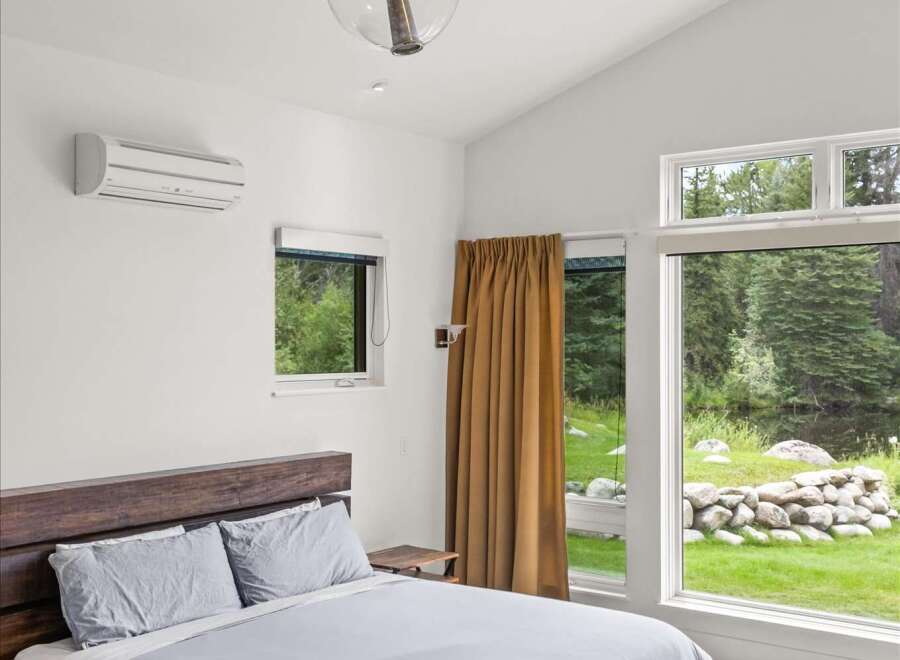 Experience serene living in this modern bedroom, featuring a spacious king-size bed with comfortable grey linens and a striking wooden platform frame.