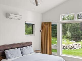 Experience serene living in this modern bedroom, featuring a spacious king-size bed with comfortable grey linens and a striking wooden platform frame.