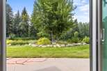 Step outside to a beautifully landscaped backyard featuring a lush green lawn, a serene water feature, and mature trees providing ample shade.