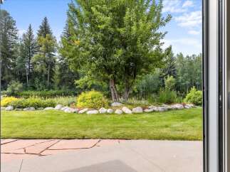 Step outside to a beautifully landscaped backyard featuring a lush green lawn, a serene water feature, and mature trees providing ample shade.