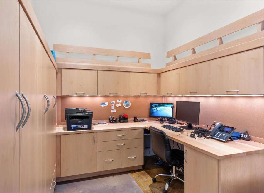 This home office features custom light wood cabinetry, providing ample storage and a clean, modern aesthetic.