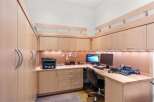 This home office features custom light wood cabinetry, providing ample storage and a clean, modern aesthetic.