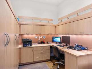 This home office features custom light wood cabinetry, providing ample storage and a clean, modern aesthetic.