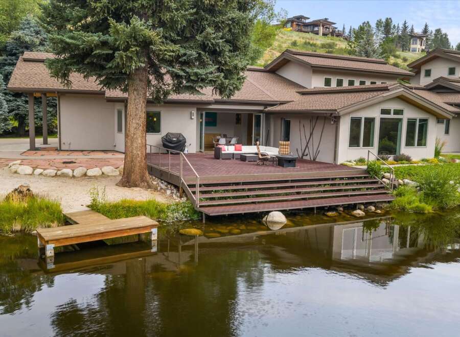 Experience luxurious lakeside living with this stunning property featuring a spacious deck overlooking a tranquil pond.