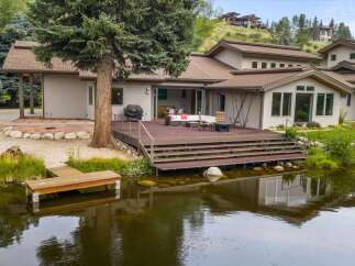 Experience luxurious lakeside living with this stunning property featuring a spacious deck overlooking a tranquil pond.