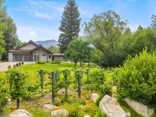 Discover this stunning property featuring a modern home with a spacious garage and a beautiful vineyard in the foreground.