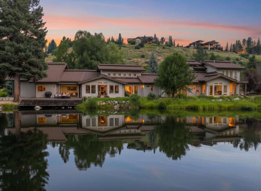 Experience luxury living with this stunning waterfront property, featuring a modern home with expansive windows and a spacious deck overlooking a serene lake.