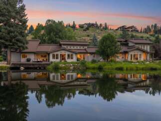Experience luxury living with this stunning waterfront property, featuring a modern home with expansive windows and a spacious deck overlooking a serene lake.