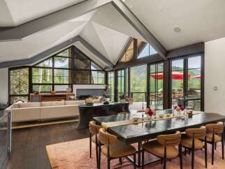 Experience luxurious mountain living in this stunning home featuring a grand dining area with a large wooden table perfect for gatherings.