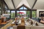 Experience luxurious mountain living in this stunning great room, featuring a soaring vaulted ceiling with exposed beams and a wall of windows offering breathtaking panoramic views.