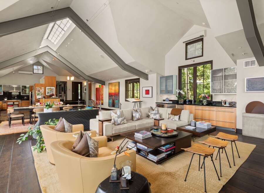 Experience luxurious living in this expansive open-concept great room, featuring a soaring vaulted ceiling with skylights and exposed beams.
