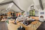 Experience luxurious living in this expansive open-concept great room, featuring a soaring vaulted ceiling with skylights and exposed beams.
