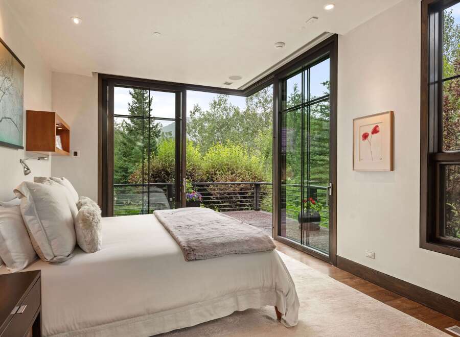 Experience luxurious mountain living in this stunning bedroom featuring a king-sized bed with plush white linens and a cozy throw blanket.